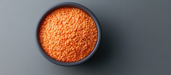 Aufkleber - Close-up of vibrant red split lentils in a dark gray bowl on a muted gray background highlighting their rich texture and color variation