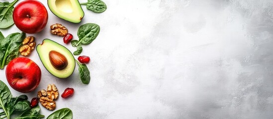 Poster - Colorful fruit salad featuring red apples, avocado, spinach, and walnuts arranged on a light gray background with ample copy space in top view flat lay.