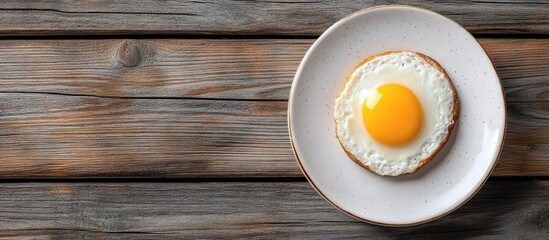 Poster - Breakfast plate with fried egg on toasted bread, positioned center-right against rustic brown wooden background, soft natural lighting.
