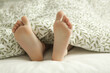 © triocean - Child feet under the green and white duvet