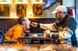 © unai - Man feeding disabled friend in restaurant, showing care and support