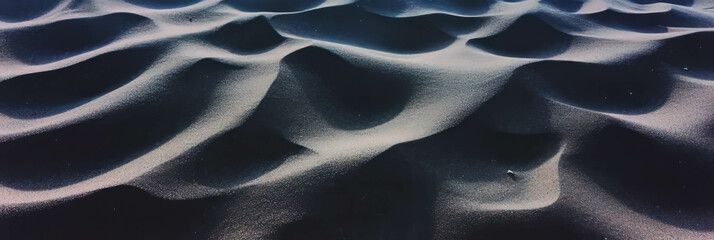 Poster - Deep footprints imprinted in loose black sand under soft shadows at dusk