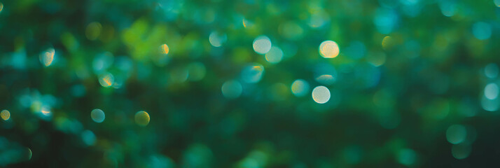 Fototapete - Textured background of sparse bokeh with gentle light reflections and green hues