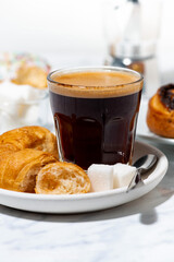 Wall Mural - black coffee in a glass, mini croissants and a sweet bun, vertical