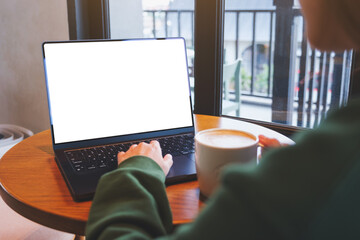 Wall Mural - Mockup image of a woman typing on laptop computer with blank white desktop screen in cafe