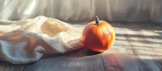Aufkleber - Small orange pumpkin on rustic wooden surface with draped cloth and soft natural light creating warm fall ambiance and space for text.
