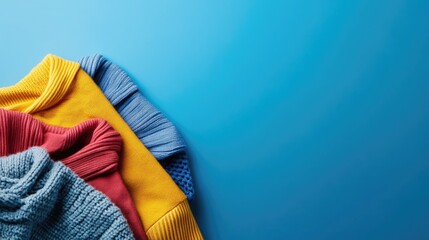 Poster - Worn colorful clothing arranged on a vibrant blue background with ample empty space for customizable text or branding elements.