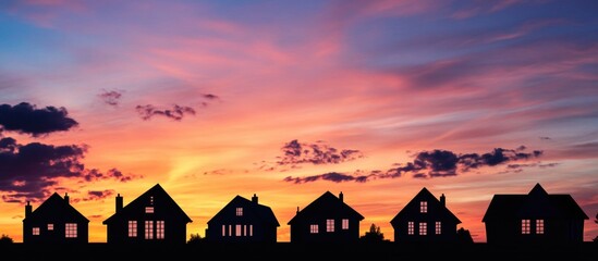 Poster - Silhouettes of urban houses against a colorful sunset sky with dramatic clouds showcasing a tranquil evening landscape.