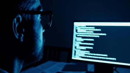 Young man focused on computer screen with code, technology cybersecurity night work concept