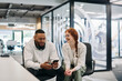 © .shock - In a modern office African American businessman and businesswoman colleague, with her striking orange hair, engage in collaborative problem-solving sessions