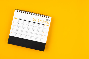 Wall Mural - October 2025 desk calendar on yellow background, position with copy space.