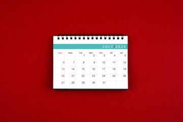 Wall Mural - July 2025 desk calendar on red background in the middle.