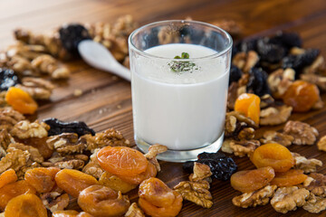 Poster - natural yogurt with nuts, dried apricots and prunes on a wooden table