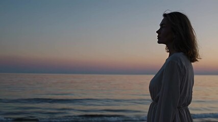 Aufkleber - Profile of a young woman with short blond hair, wearing a light dress, gazing at the ocean at sunset, creating a peaceful and contemplative scene, captured in slow motion