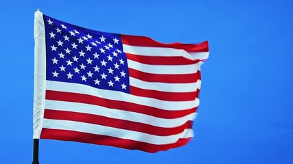 Wall Mural - Slow motion video of American flag waving on blue sky background