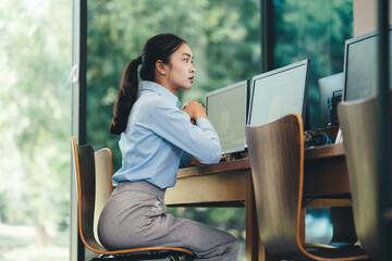 Poster - Professional businesswoman working intently on dual monitor setup, natural light illuminating sleek modern office workspace, embodying corporate productivity and concentration