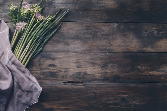 Rustic wooden background with fresh green onions and a napkin, top-down view with space for text