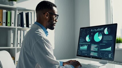 Poster - Professional medical scientist wearing lab coat analyzing data charts and diagrams displayed on computer screen in bright modern office in slow motion
