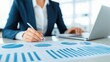 © Manon - A business professional analyzes charts and graphs while working on a laptop, emphasizing data-driven decision-making in a modern office setting.