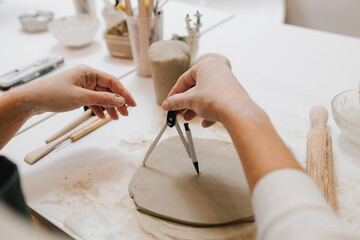 Poster - Artisan with compass shapes and refines a ceramic piece with precision. Potter works on a clay slab with compass.