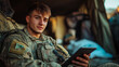 © sorasat - soldier in uniform sits in tent, holding tablet and smiling confidently