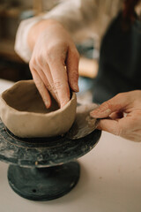 Poster - Craftswoman carefully molds a clay bowl on the potters wheel. Creating ceramic crockery in the workshop.