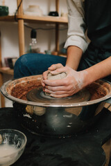 Poster - Artisan molds a piece of wet clay on the pottery wheel. Process of making ceramic earthenware on the spinning wheel in the pottery studio.