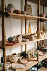 Poster - Shelf with handmade clay cups and plates in the pottery studio. Creating ceramics ware with own hands.