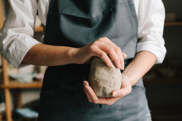 Fototapete - Potter holds a piece of wet clay in their hands, molds it into form. Process of creating ceramic products.
