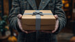 © coffeeflavour - A gift packet with a grey ribbon is held by male hands.