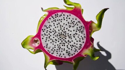 Aufkleber - Vibrant pink dragon fruit halves rotating symmetrically, revealing intricate seed patterns and showcasing natural textural details against pristine white background
