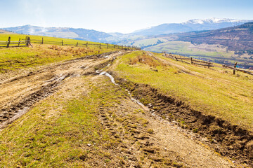 Wall Mural - rural road through the hill with grassy meadow. sunny day. carpathian mountain ridge in the distance