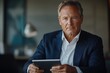 © stockphoto02 - A serious-looking businessman in a navy suit holds a tablet, appearing focused and professional.