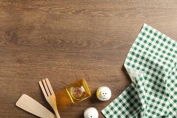 Wall Mural - Checkered tablecloth, cooking utensils, oil and spices on wooden table, flat lay. Space for text