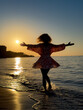 © Sunny studio - Silhouette of young woman dancing at the sandy beach