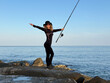 © Sunny studio - Young happy woman is fishing at sea during spring vacation