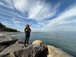 © Sunny studio - Young happy woman is fishing at sea during spring vacation