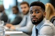 © Guy - Focused and Determined: A young black businessman in a crisp, light blue shirt and a dark tie looks directly at the camera with a focused expression.