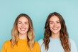 © Andrei - vibrant portrait of two smiling friends captured against smooth pastel blue solid background with even lighting and
