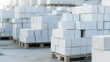© Curioso.Photography - Stacks of neatly arranged white construction blocks placed on wooden pallets at an industrial storage site.