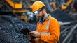 © afif - Miner reviewing data on tablet, coal mine, heavy machinery