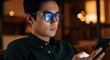 © Tati - Asian man using smartphone in low light environment