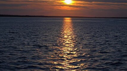 Wall Mural - slow motion shot of a breathtaking sunset over vast water – radiant sun near the horizon, golden hue