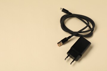 Wall Mural - USB power adapter with charge cable on beige background, above view. Space for text