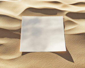 Poster - A blank white sheet of paper placed on a sandy surface with soft shadows, symbolizing space for creativity, design, and text, ideal for mockups and advertising.