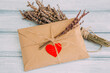 © RooM The Agency - Close-up of a brown Envelope sealed with a heart sticker, brown string and decorated with dried flowers on a wooden table