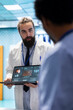 © DC Studio - Neurology specialist examines magnetic resonance imaging brain scan with his team in a meeting, looking at tomography for accurate neuroscience diagnosis. Diverse team of neurologist doctors.