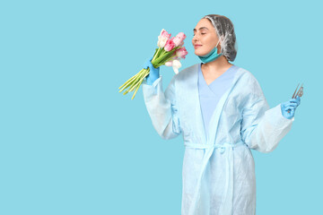 Canvas Print - Portrait of young female surgeon with bouquet of flowers and surgical instruments on blue background. International Women's Day