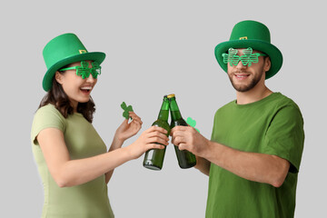 Wall Mural - Happy young couple in leprechaun hats with bottles of beer and clover on grey background. St. Patrick's Day celebration