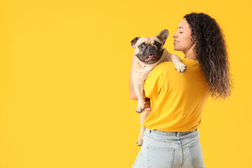 Wall Mural - Beautiful young African-American woman with cute French bulldog on yellow background